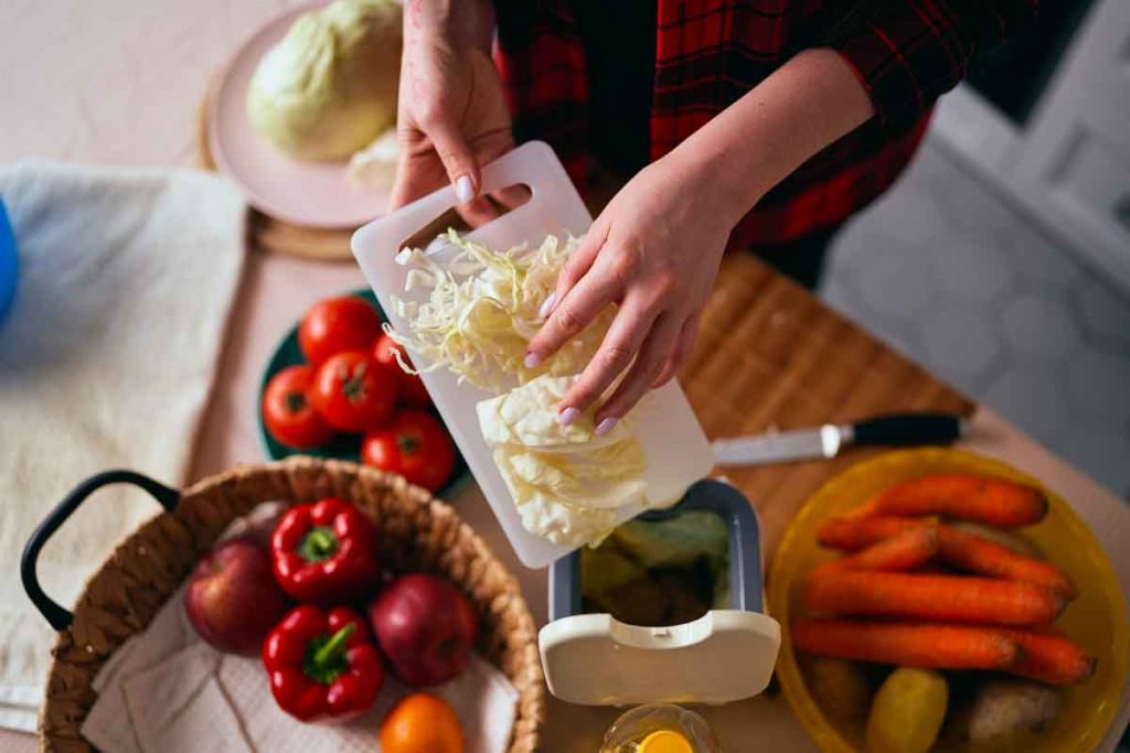 Housewife cooking healthy salad at home and throwing food leftov
